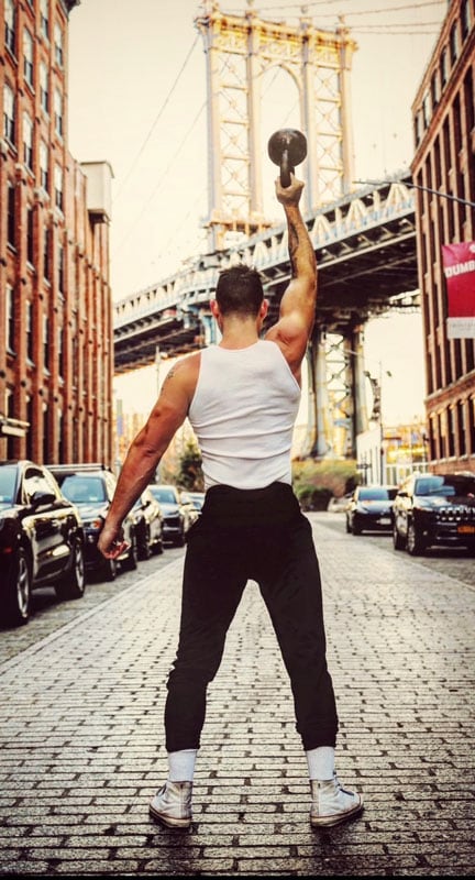 The coach demonstrates an overhead lift with a kettlebell.